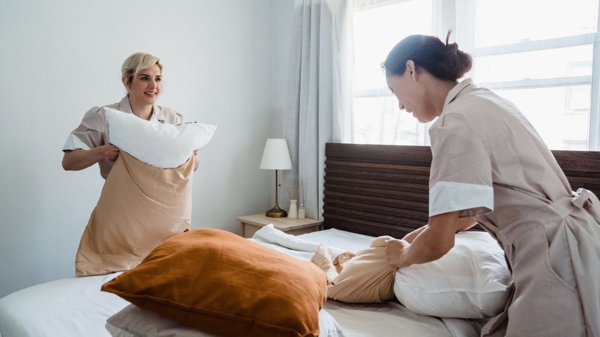 Deux professionnelles du ménage refaisant un lit dans une chambre lumineuse